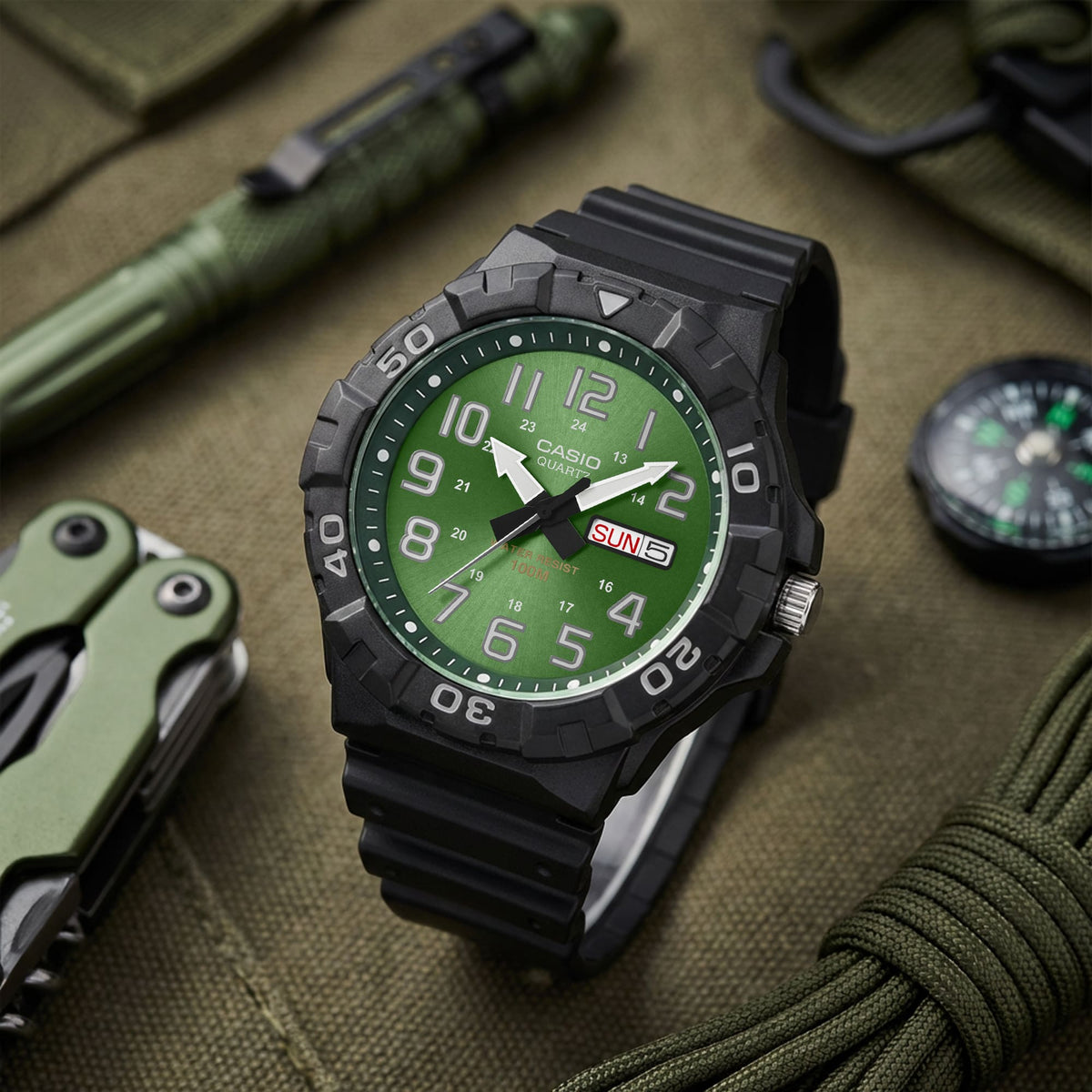 Reloj de buceo con esfera verde junto a equipo de campo