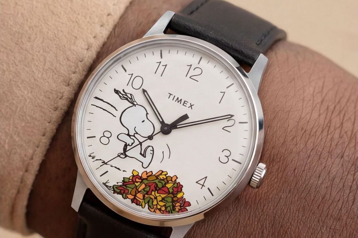 Timex Waterbury × Peanuts en la muñeca, con Snoopy saltando sobre un montón de hojas