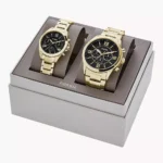 Set de relojes Fossil BQ2400SET en caja de presentación, con diseño en acero inoxidable dorado y esfera negra.