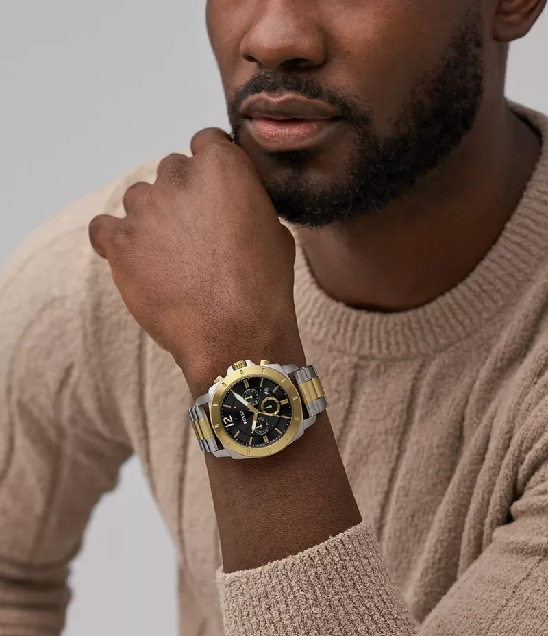 Hombre usando el reloj Fossil Privateer, mostrando su estilo elegante con el dial negro y correa bicolor.