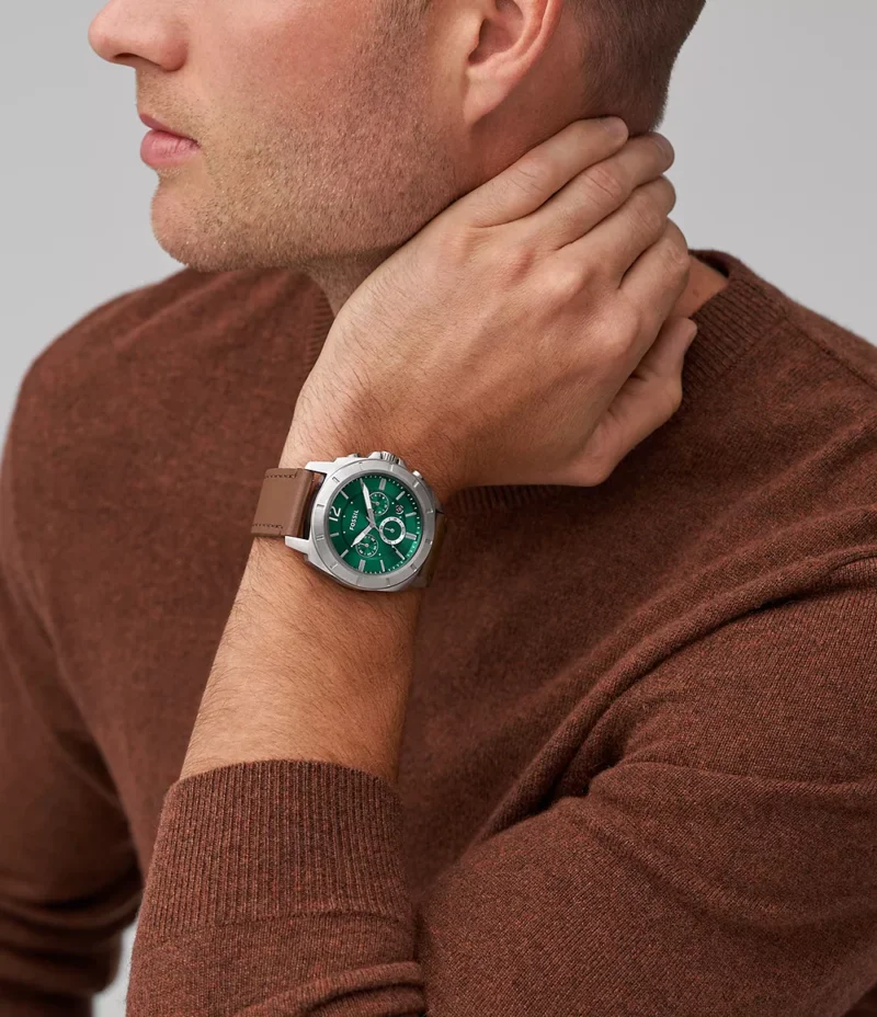 Hombre usando el reloj Fossil Privateer, mostrando su diseño moderno con el dial verde y correa de cuero marrón.